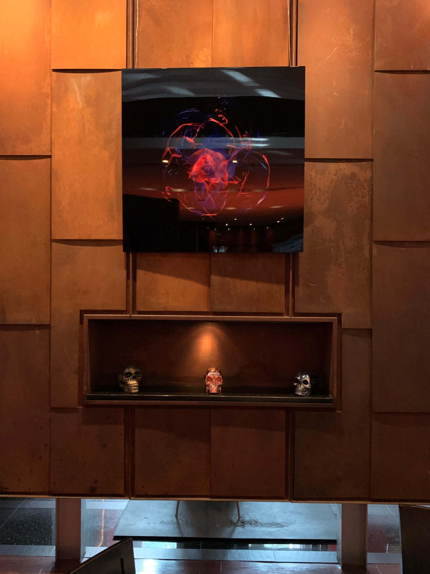Contemporary artwork and sculpted skulls staged in a corten-steel dining space