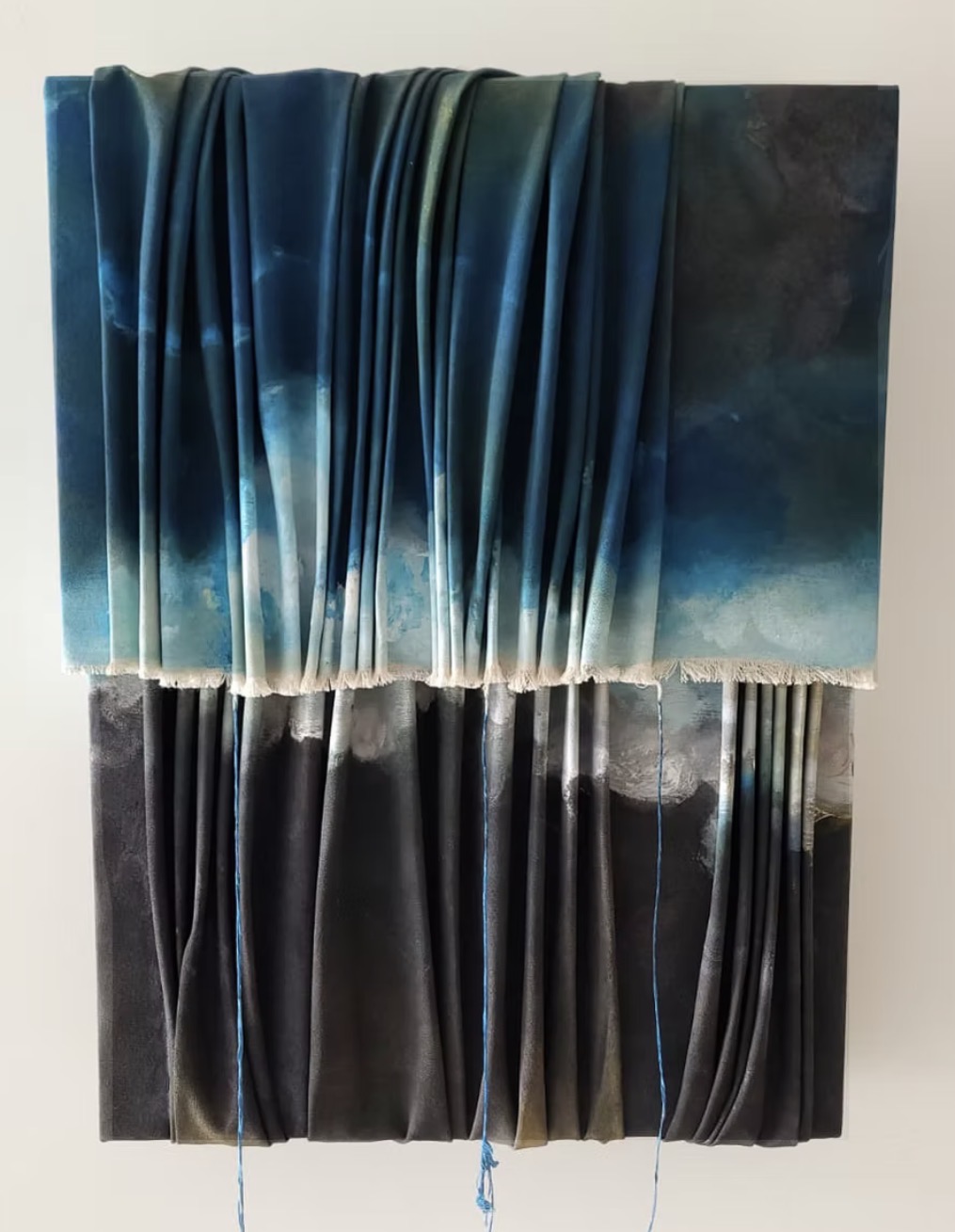 Two-part draped fabric composition in deep blue and charcoal with loose threads